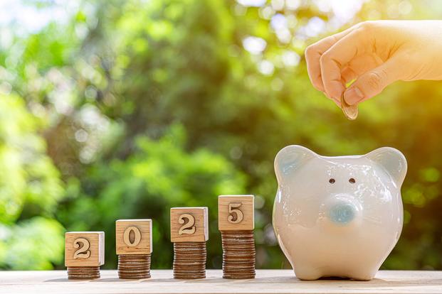 Four stacks of coins with the digits of 2025 on top increase in size from left to right until arriving at a white piggy bank.