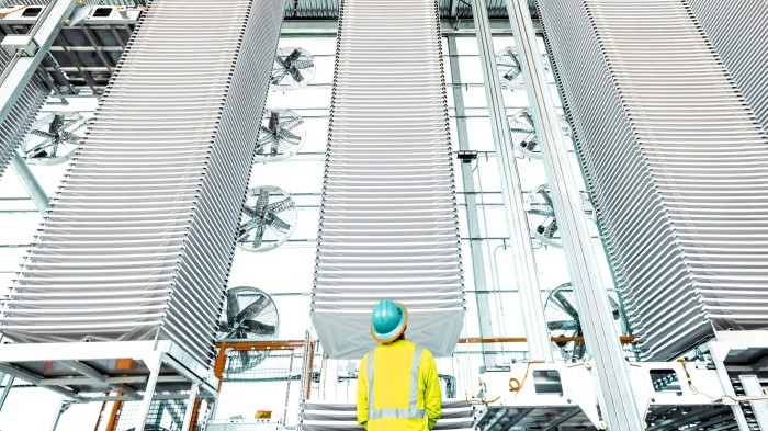 A worker in a hard hat looks at stacks of trays holding treated limestone, used to absorb carbon dioxide from the air